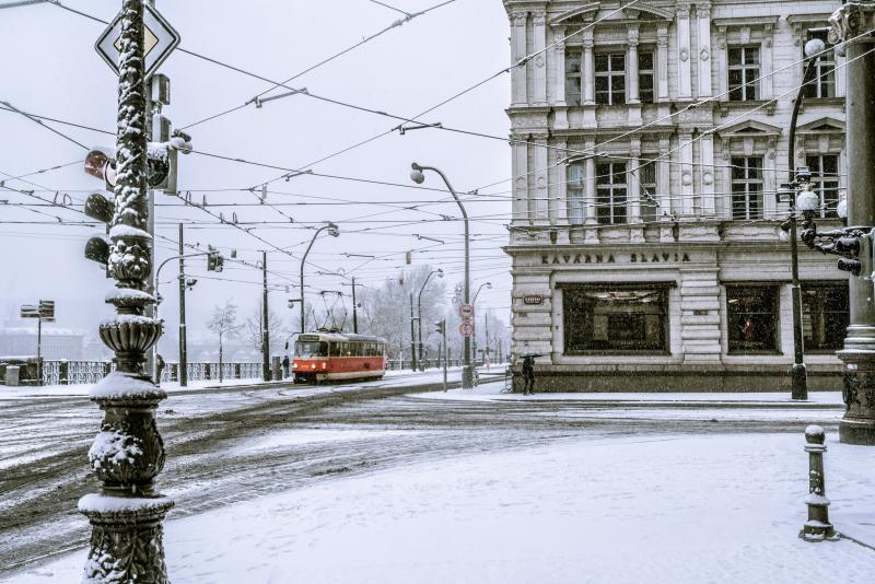 Tram travels through a snowy cityscape.
